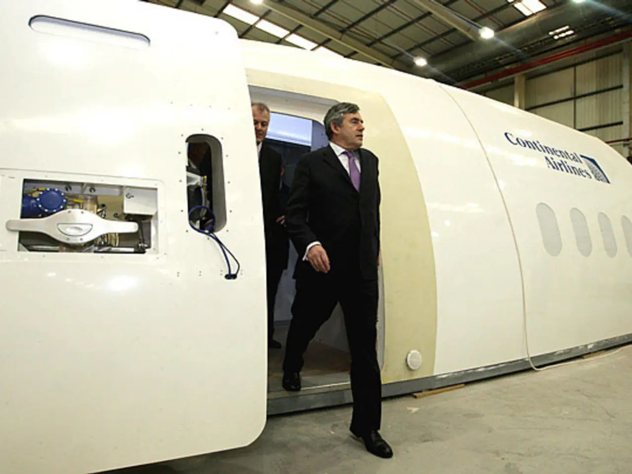 In the center of the image there is an aircraft prototype and we can see two persons. On the...