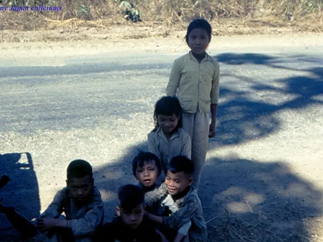 In the picture we can see a road on it, we can see a dried grass on either side and some children...
